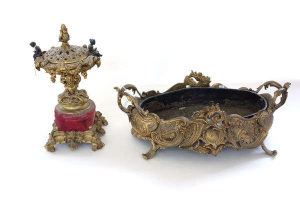 A French gilt bronze urn and cover, late 19th century, with foliate surmount and figural handles, ornately cast on a velvet cushion and scroll base, 3