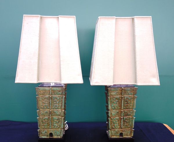 A pair of modern patinated table lamps of archaic Chinese form, each adjustable on a wooden base, with shaped silk shades, 48cm high excluding shades.