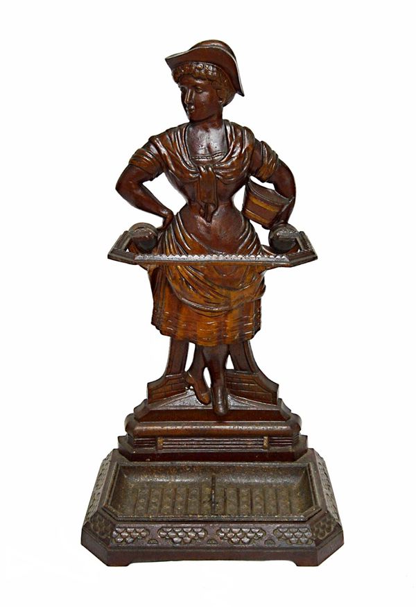A Coalbrookdale cast iron stick stand, mid 19th century, modelled and cast as a female market seller, on a canted rectangular base with removable drip