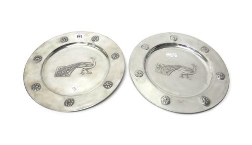 Two Liberty & Co Arts and Crafts pewter chargers, early 20th century, one decorated with a peacock to the centre and worked in relief with seven space