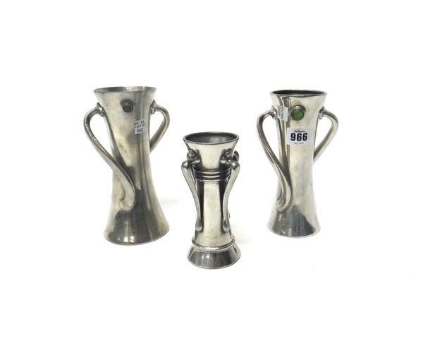 Two Liberty & Co Tudric pewter vases, of twisted two handled form, the largest numbered 051, 18.7cm high, and one similar smaller vase. (3)