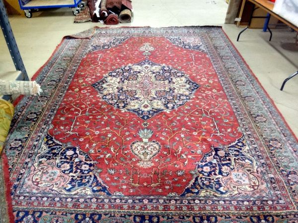 A Tabriz carpet, the claret red field with central blue and white Coptic cross design medallion within similar spandrels and green floral main border,