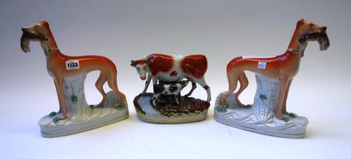 A pair of Staffordshire flatback greyhounds, 19th century, each with a rabbit in its mouth, on a naturalistic base, 28.5cm high, and a Staffordshire f