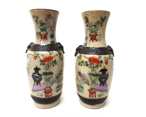 A pair of Chinese crackleware vases, late 19th century, painted with vases, flowers and tables, set with lion mask and ring handles, 25cm. high.