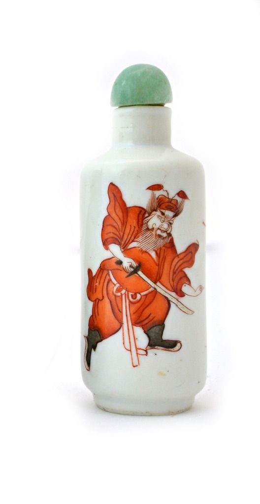 A Chinese porcelain snuff bottle, late 19th/20th century, of cylindrical form painted in iron-red with a bearded figure brandishing a sword beside two