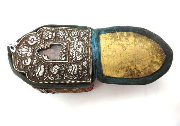 A Tibetan portable shrine, late 19th century, the silver repousse top decorated with emblems around a central glass arch revealing a wax figure of Bud