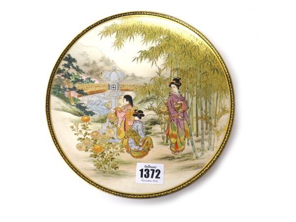 A Japanese Satsuma plate, Meiji period, painted with three bijin in a landscape, a shrine and bridge crossing a river in the distance, signed, 21.5cm.