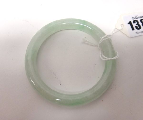 A Chinese jade bangle, the stone of pale celadon tone with apple green and white inclusions, 7.5cm. to outer rim.