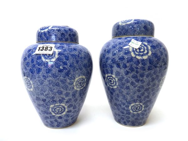 A pair of Japanese Seto ware blue and white ovoid vases and covers, Meiji period, each painted with peony against a dense foliate ground, blue painted