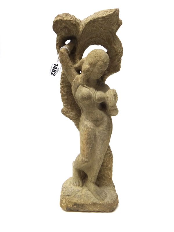 An Indian sandstone figure of a gopi, late 19th/20th century, carved standing against a tree, 45cm. high