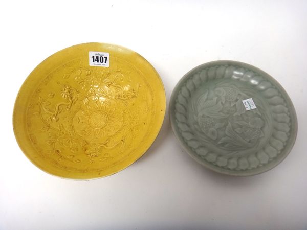 A Chinese yellow ground deep bowl, 20th century, moulded in the centre with a four character mark beneath three dragons amongst flowers, (a.f), 20cm.d