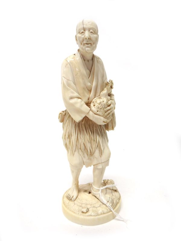 A Japanese ivory okimono of a man gathering coral by Ju/Toshi, Meiji period, standing with shells at his feet holding a branch of coral with both hand