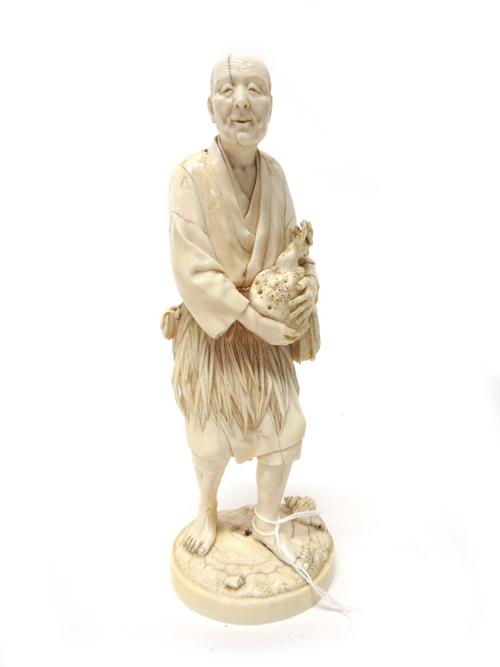 A Japanese ivory okimono of a man gathering coral by Ju/Toshi, Meiji period, standing with shells at his feet holding a branch of coral with both hand