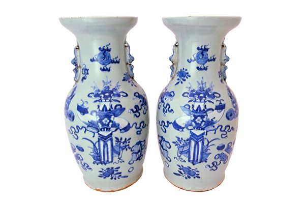 A pair of Chinese celadon ground blue and white baluster vases, late 19th century, painted with vases, stands, fruit and emblems, set with buddist lio