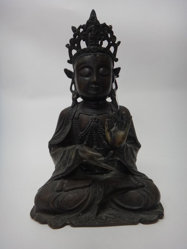 A large Chinese Ming style figure of Guanyin, seated crossed-legged with left hand raised, wearing an elaborate headress, her face with a serene expre
