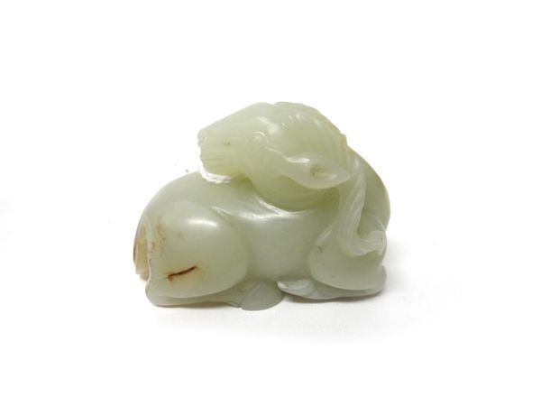 A Chinese pale celadon jade ram, the animal carved in recumbent pose with head turned across its back, the stone with russet inclusions, 5.5cm.length.
