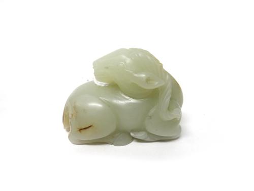 A Chinese pale celadon jade ram, the animal carved in recumbent pose with head turned across its back, the stone with russet inclusions, 5.5cm.length.