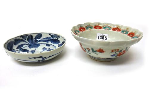 A Japanese kakiemon fluted bowl, early 18th century, painted with flowering shrubs issuing from blue rocks, (a.f.) 15cm. diameter, G. & C.W. Digby col