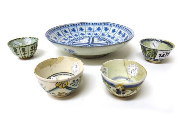 Four Kutahya pottery teabowls, 18th century, each painted with floral designs, (a.f); and an Iranian blue and white fritware plate, (a.f), 20.5cm.diam