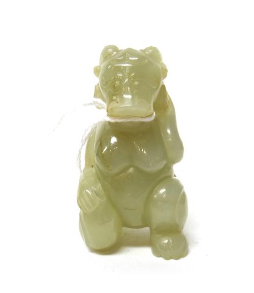 A Chinese pale celadon jade mythical creature, with ram's head and human body, carved in kneeling pose, the stone with russet inclusions, 6.5cm. high.