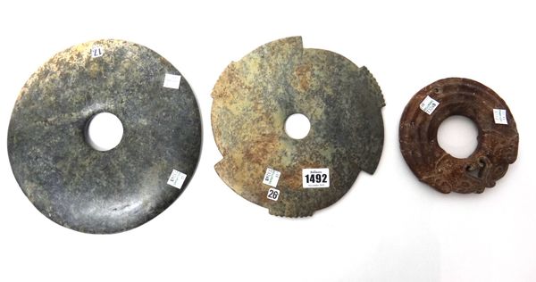 Six large Chinese jade bi discs, of various colours, one carved as two confronting dragons, 14cm. to 23cm. wide.