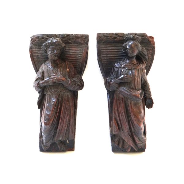 Two 17th century carved oak figural finials, on scroll mounts, 14cm wide x 26cm high. (2) Illustrated.