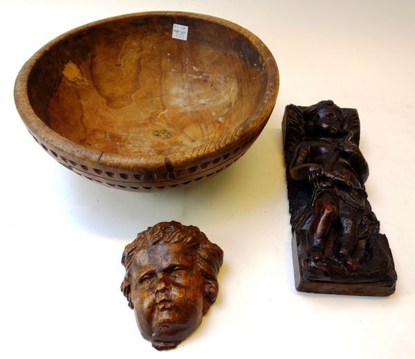 A 17th century carved walnut fragment of a cherub standing on a serpent, 8.5cm wide x 22cm high, together with a further carved face mask of a cherub,