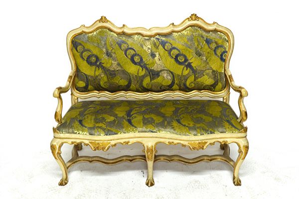 An 18th century North Italian cream and parcel gilt painted sofa, with shaped padded back and seat, on six cabriole supports, 130cm wide. Illustrated.