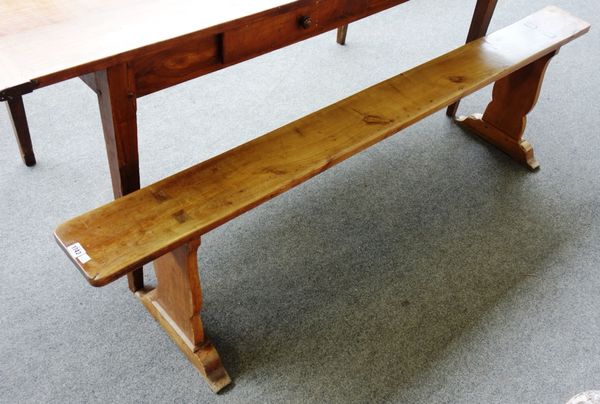 A pair of 19th century French fruitwood benches on silhouette trestle end supports, each 185cm wide (2).