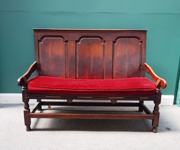A George II oak settle, with triple arch panel back and open arms, on turned supports, 140cm wide.