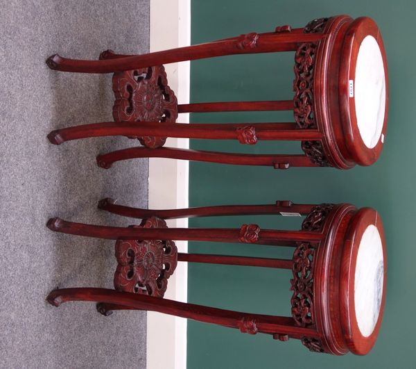 A pair of 20th century Chinese urn stands, each with marble inset circular top over a pierced and carved hardwood base, 32cm wide.