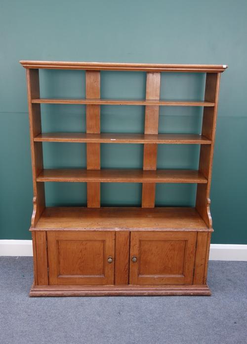 A 19th century scumble painted pine bookcase cupboard, the four open tiers above a pair of panel cupboards, 128cm wide x 159cm high.