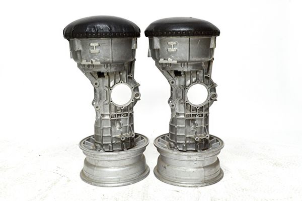 A pair of 20th century bar stools, the padded circular tops on polished steel engine components and alloy wheel bases (2). Illustrated.