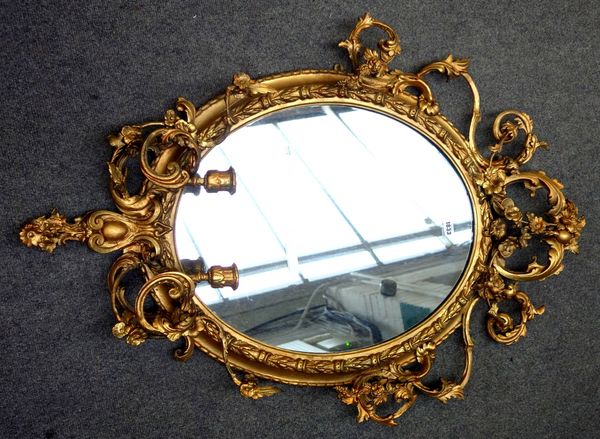 A Victorian gilt framed oval wall mirror, relief chased with floral sprays, mounted with twin branch candelabra, 75cm wide x 100cm high.