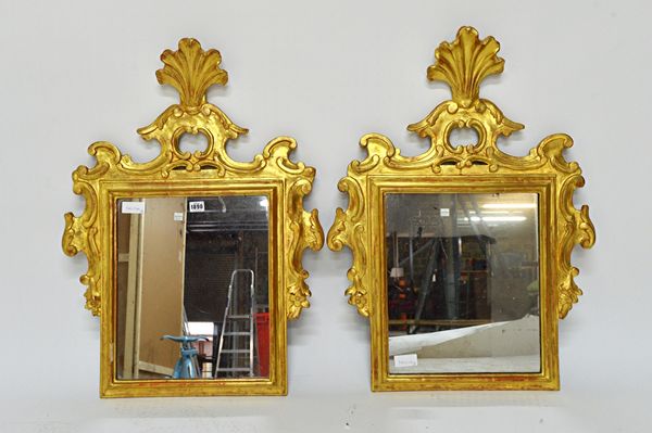 A pair of 19th century Italian gilt frame wall mirrors, each with pierced opposing C-scroll crest about the shaped frame, 59cm wide x 78cm high. Illus