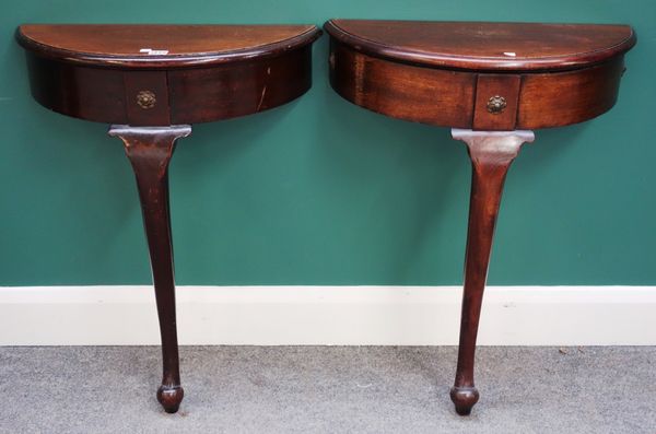 A pair of 18th century style walnut semi-elliptic consoles on single cabriole supports, each 61cm wide. Property from the estates of the late Adrian S