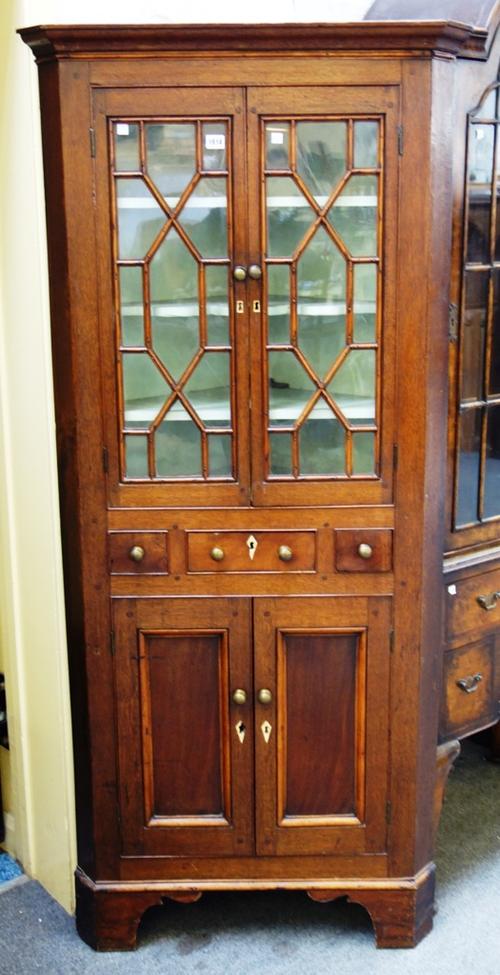A George III oak floor standing corner display cabinet/cupboard, the pair of astragal glazed doors over single drawer and further pair of cupboards, o
