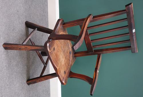 An early 19th century oak and fruitwood stick back Windsor chair, with saddle seat, on splayed tapering chamfered square supports, carved to the under