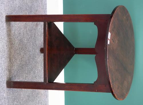 A George III oak cricket table, the circular top on three triangular supports, united by platform undertier, 53cm wide.