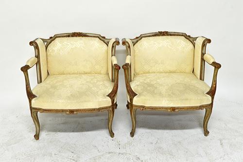 A pair of early 20th century French parcel gilt grey painted boudoir chairs, each with outswept square back, open arms and bow seat, on cabriole suppo