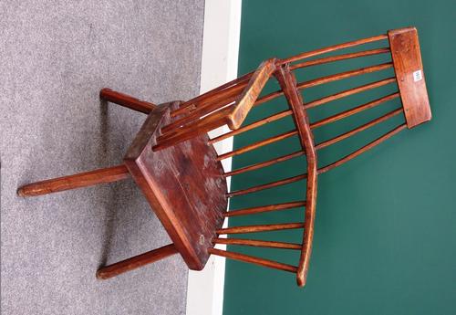An 18th century style primitive comb/bow back Windsor chair with solid seat on four staked supports.