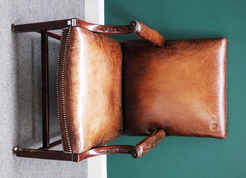 A 19th century Gainsborough style open armchair with carved down swept arm supports on block legs, united by H frame stretcher.