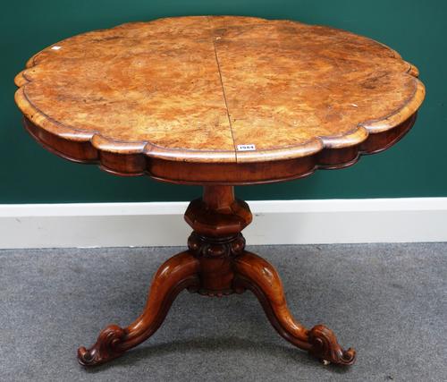A Victorian figured walnut occasional table, the shaped snap top on baluster octagonal column and three downswept supports.Property from the estates o