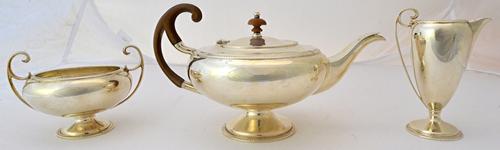 A silver three piece tea set, comprising; a teapot, with wooden fittings, a twin handled sugar bowl and a milk jug, each piece of classical form with