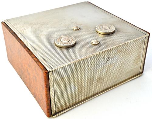A silver and wooden table cigarette box, the hinged lid with a twin dial combination opening mechanism, otherwise engine turned, the sides of the box