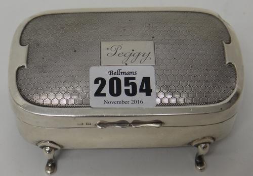 A silver curved rectangular jewellery box, the engine turned lid detailed 'Peggy' to the centre and raised on four feet, Birmingham 1928.