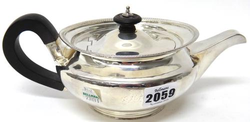 A George III silver teapot, of squat circular form, with later black fittings and with a gadrooned rim, maker R & S Hennell, London 1804, gross weight
