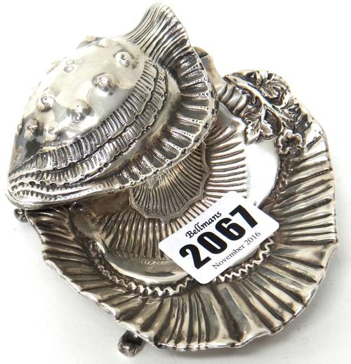 A Victorian silver inkstand, the hinged cover formed as a shell, raised on four feet, Birmingham 1893, fitted with a glass oval ink bottle, the mount