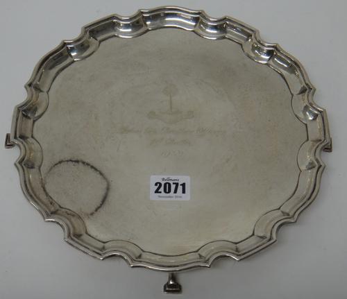 A silver salver, of shaped circular form, with a pie-crust rim, crest and presentation inscribed to the centre, raised on four pad feet, Birmingham 19