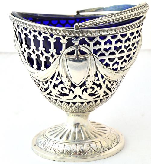 A silver sugar basket of urn shaped form, pierced and embossed with linen fold swags, within a gadrooned rim and with a swingover handle, in the late